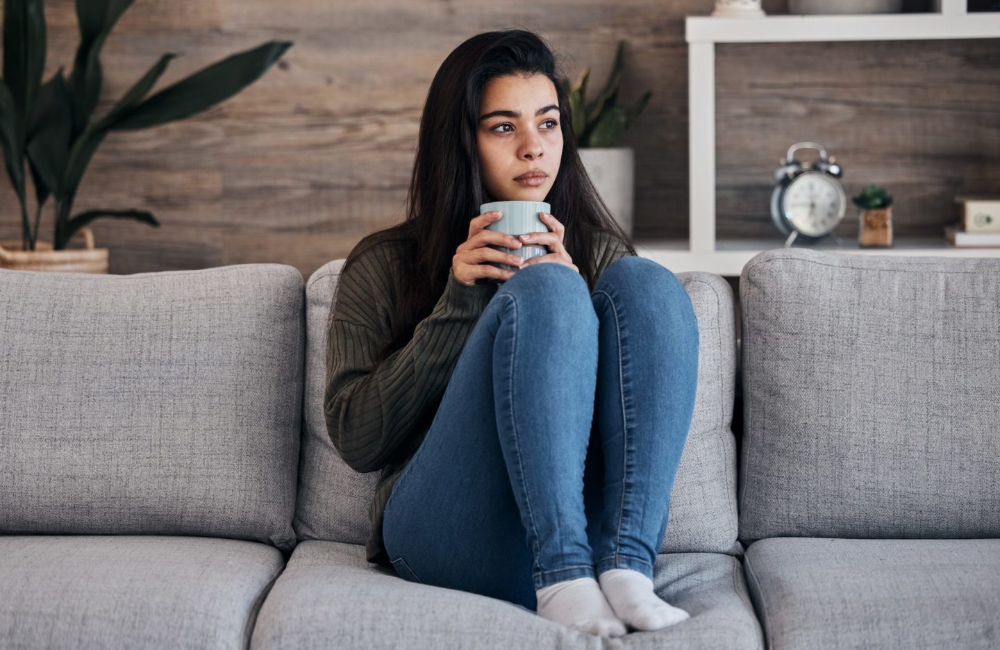 depression-sad-and-woman-with-coffee-on-a-sofa-for-thinking-lonely-and-isolated-in-a-living-room--e1678254761361.jpg